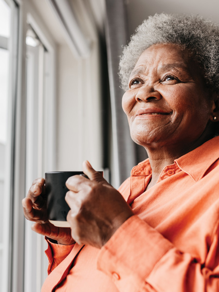 Woman drinking from a mug looking out of window.jpg