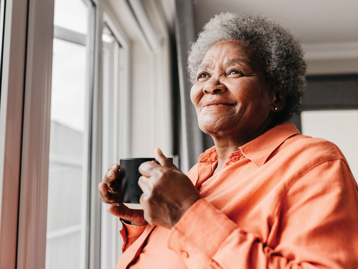 Woman drinking from a mug looking out of window.jpg