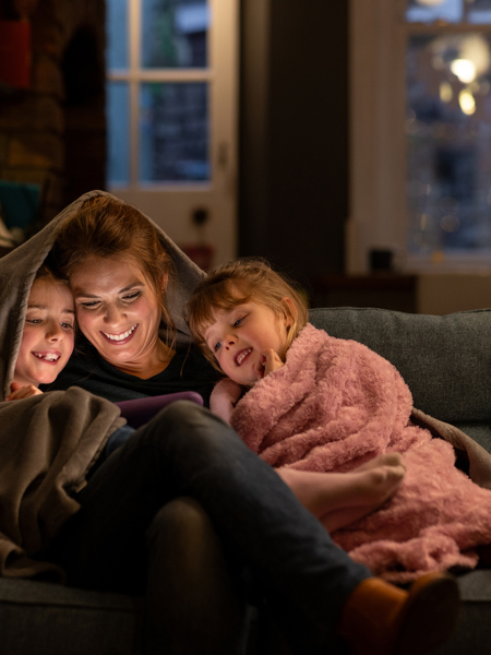 Adult with two children on the sofa at nighttime with a screen.jpg