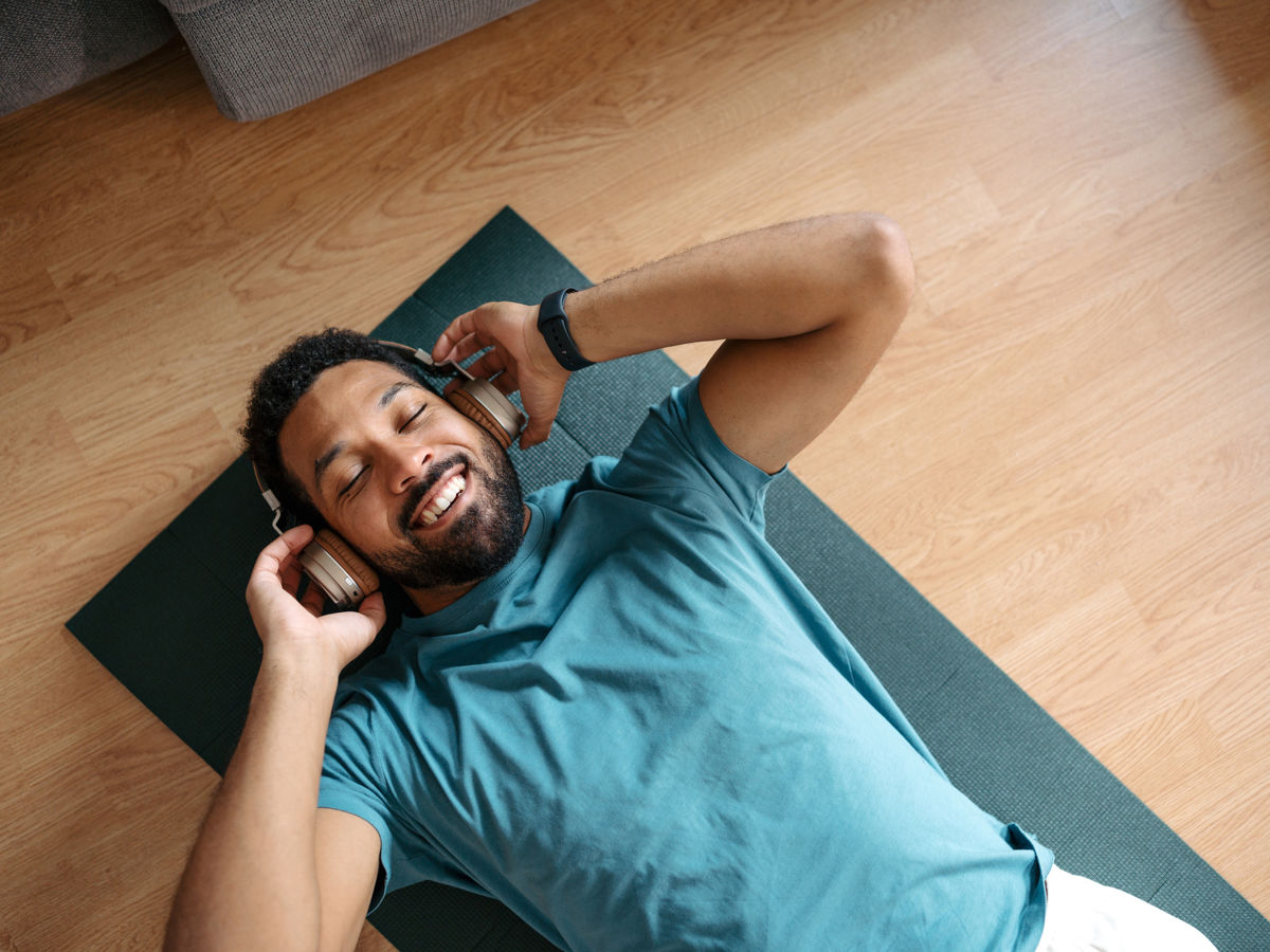 Man lying on exercise mat wearing headphones.jpg